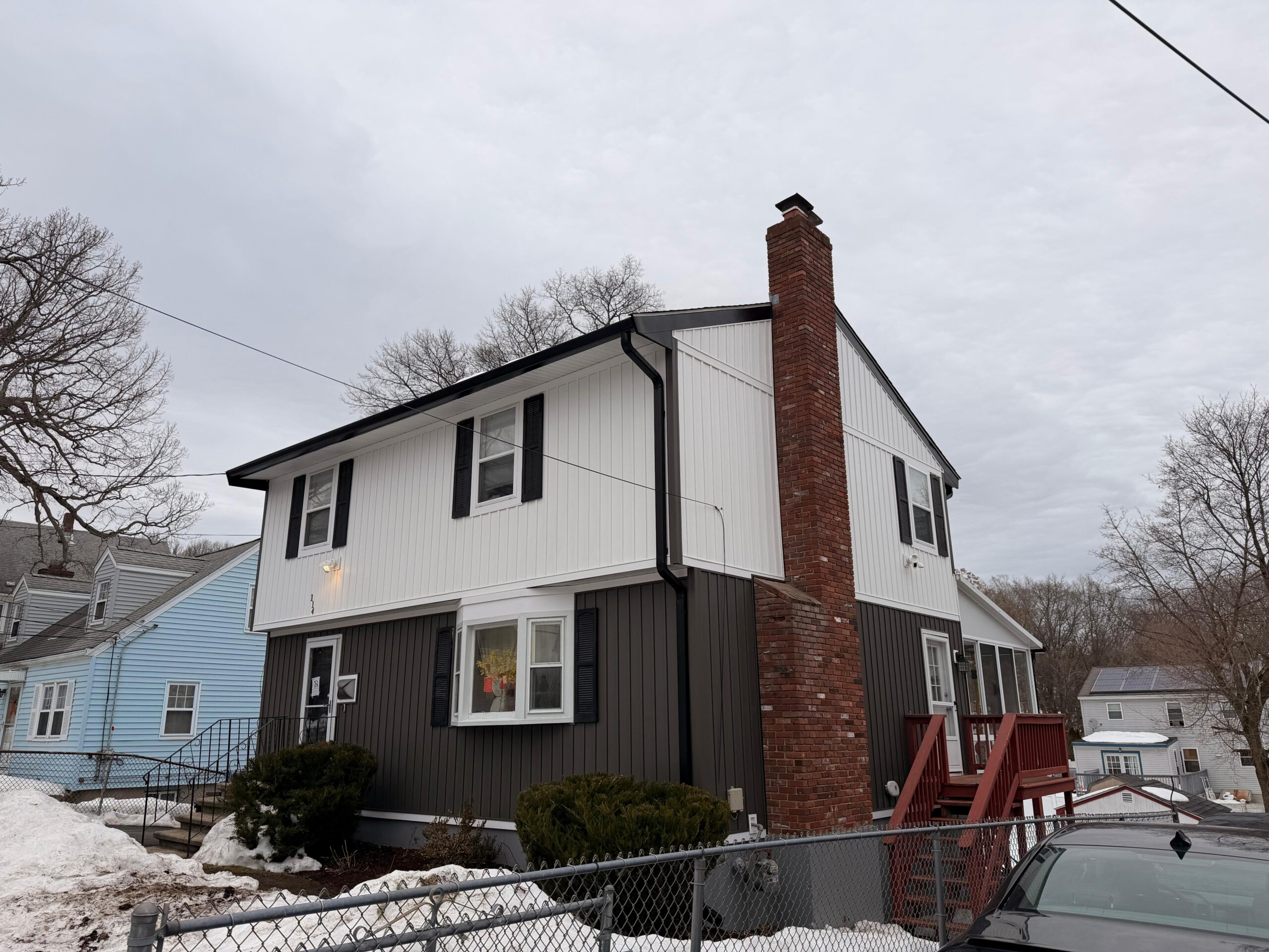 Finished two-tone board and batten siding installation in white and charcoal gray by Titanium Painting & Renovation.